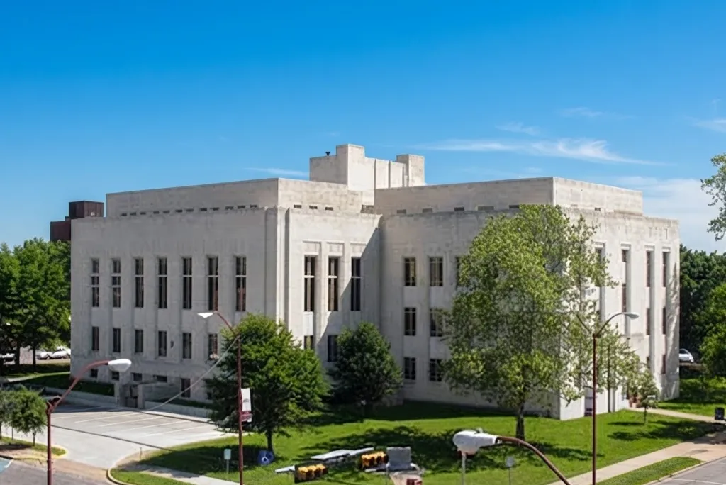 The Grayson County courthouse, a pale stone building with a flat roof and rows of narrow windows beside a green lawn.