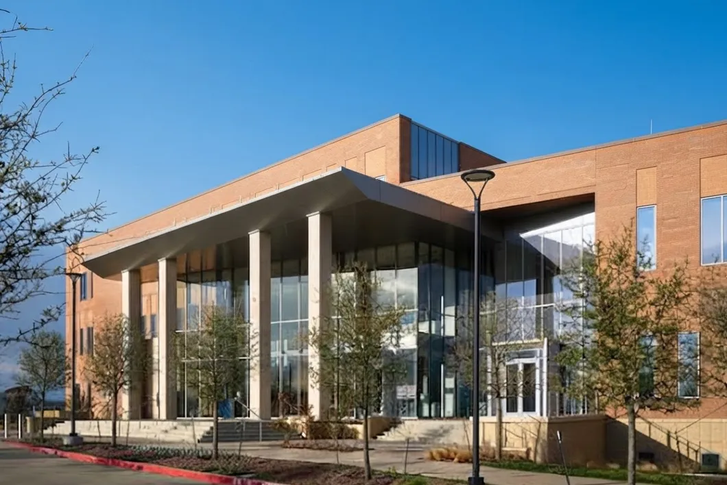 The Kaufman County courthouse, a modern brick and glass building with a deep covered entrance and young trees.