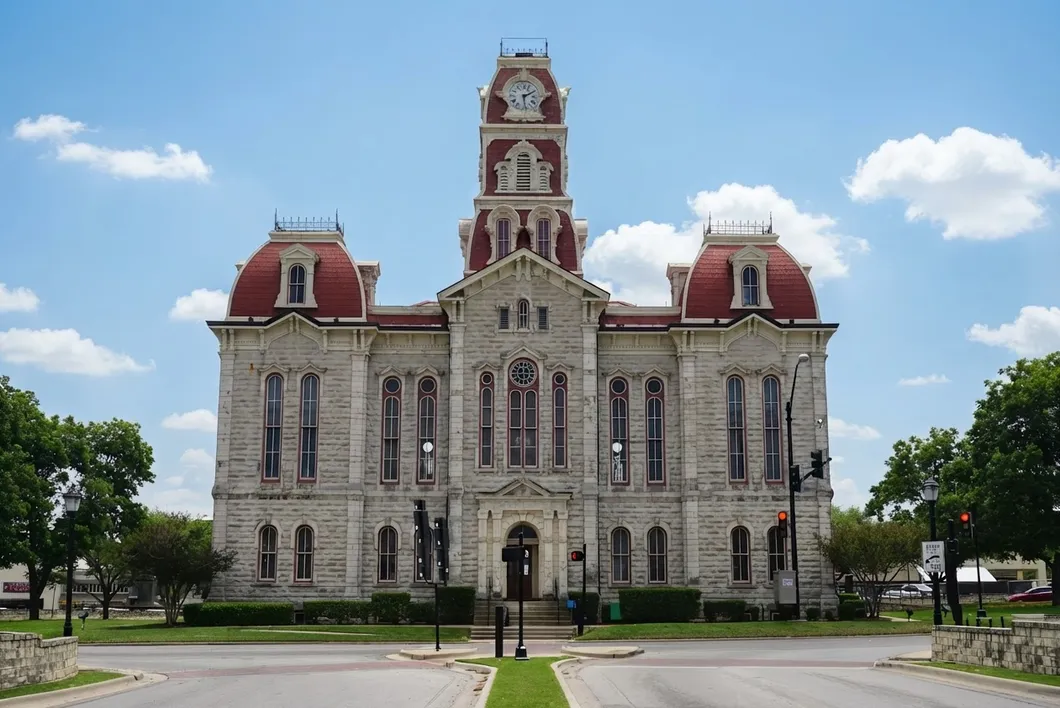 The Parker County courthouse, a gray stone building with a central clock tower and red-roofed corner pavilions.
