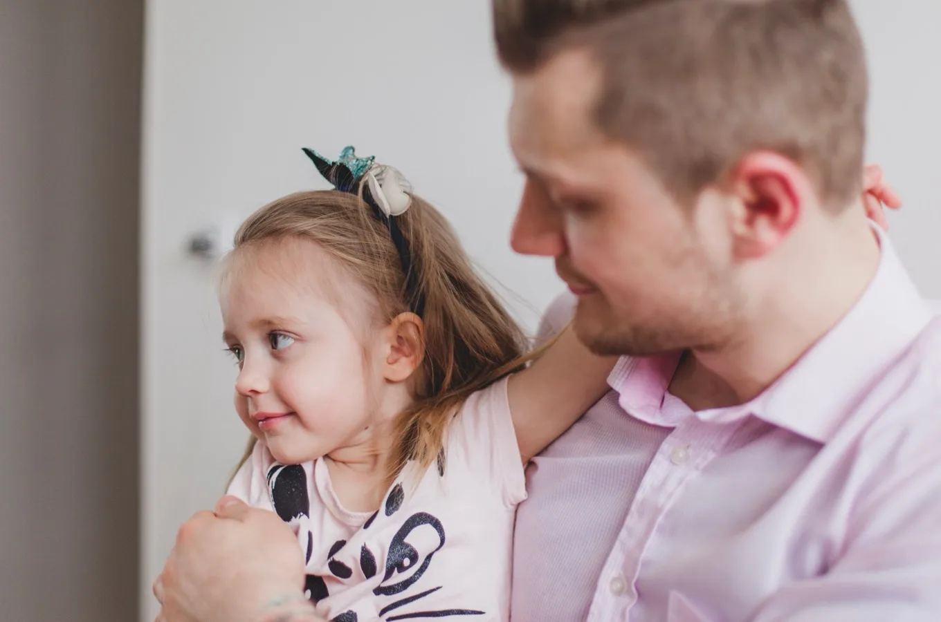 A father holding his young daughter, who looks off to the side