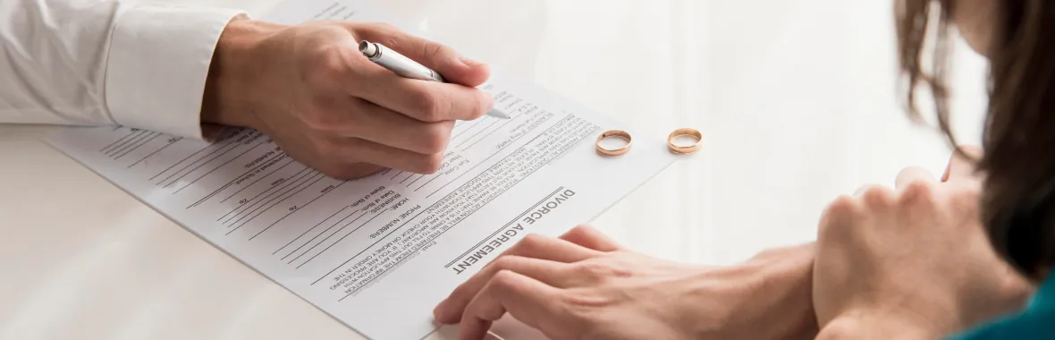 Wedding rings resting on a signed divorce agreement